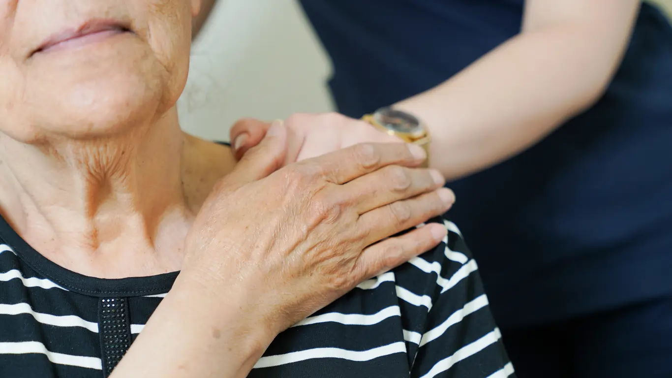 Elderly woman receiving compassionate support from caregiver, highlighting person-centred disability support services.