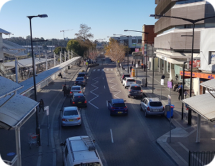 Street view of a busy urban area in Western Sydney, showcasing vehicles on the road, pedestrians, and buildings, reflecting the community environment serviced by Ability to Achieve.