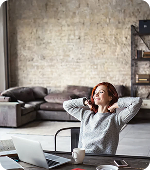 Woman relaxing in a modern workspace with a laptop and coffee, embodying independence and comfort in a supportive environment.