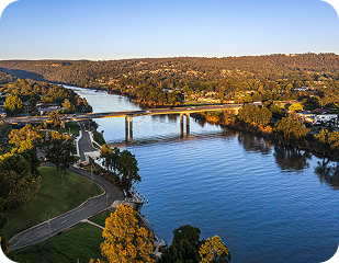 Aerial view of a serene river landscape in Western Sydney, featuring a bridge, lush greenery, and a pathway, representing the areas serviced by Ability to Achieve, including Penrith and surrounding suburbs.