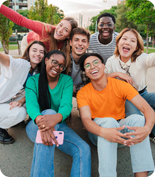 Group of diverse young adults smiling and posing together outdoors, reflecting community spirit and connection, relevant to Ability to Achieve's inclusive disability support services in Parramatta.