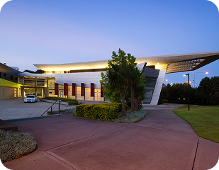 Modern building exterior with landscaped pathway, illuminated at dusk, representing Ability to Achieve's commitment to accessible disability services in Western and South Sydney.