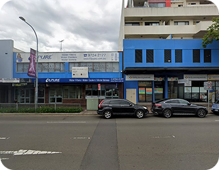 Street view of a commercial building in a service area for Ability to Achieve, featuring businesses and signage relevant to disability services in Western and South Sydney.