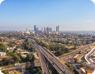 Aerial view of Sydney skyline with highways and urban landscape, representing the service areas of Ability to Achieve in Western and South Sydney.