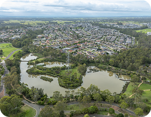 Aerial view of suburban landscape in Western Sydney featuring residential areas, green parks, and winding waterways, relevant to Ability to Achieve's service regions.