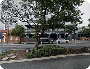 Tree in foreground with a view of a hotel building and parked cars, representing community areas serviced by Ability to Achieve in Western and South Sydney.