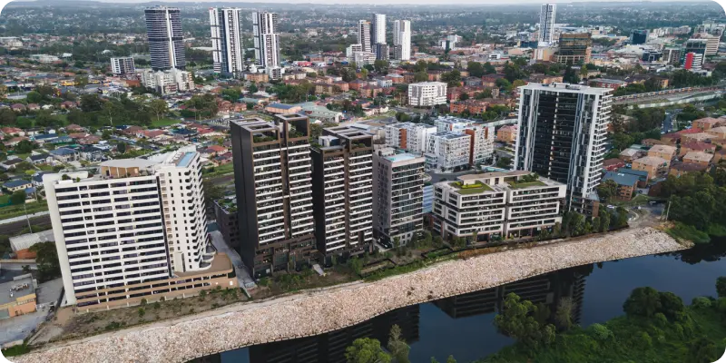 Aerial view of modern residential buildings along the riverbank in Liverpool, showcasing the vibrant urban landscape and community integration relevant to disability support services.