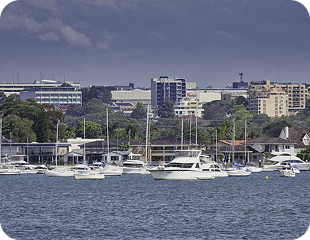 Harbor view with sailboats and city skyline, representing the service areas of Ability to Achieve in Western and South Sydney.