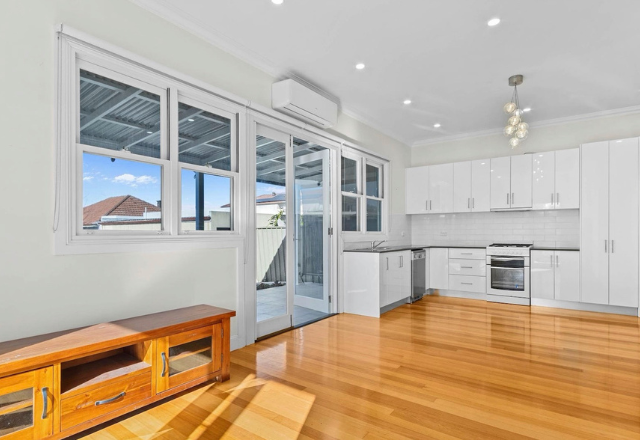 Modern kitchen interior with wooden flooring, white cabinetry, and large windows, showcasing a bright and airy atmosphere ideal for supported independent living.
