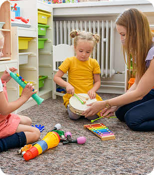 Children engaging in music therapy activities with instruments, including a tambourine and xylophone, in a supportive environment promoting creativity and social interaction.
