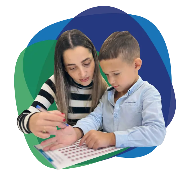 Woman assisting a young boy with a learning activity, emphasizing support and development in a nurturing environment, aligned with Ability to Achieve's focus on empowerment and tailored disability services.