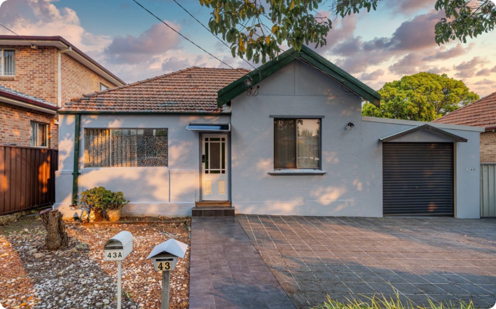 Mortdale home exterior featuring a modern single-storey design, landscaped front yard with mailboxes, and a welcoming entrance, highlighting supported independent living accommodations by Ability to Achieve.